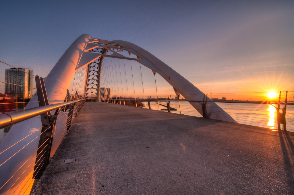 Humber Bay Arch Bridge at sunrise with a view of the CN Tower across the water