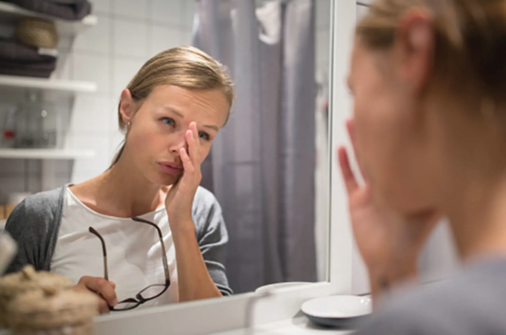 Woman looking in mirror, burned out