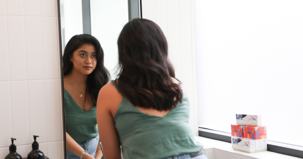 Young woman staring at herself in the mirror.